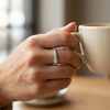 Ring on a hand holding a coffee cup