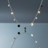Stainless steel disc charm necklace floating on blue grey gloss background with mirror reflection