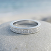 Close-up of a single silver-tone stone-set ring on coastal stone