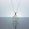 Stainless steel Tree of Life round pendant necklace on light blue grey gloss background with mirror reflection