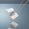 Stainless steel love you envelope locket necklace on blue grey gloss background with mirror reflection