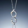 Circular white zirconia stainless steel necklace on blue grey gloss background with mirror reflection